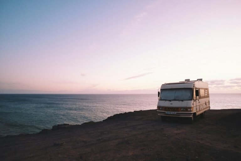 RV parked beside the edge of an island during sunset