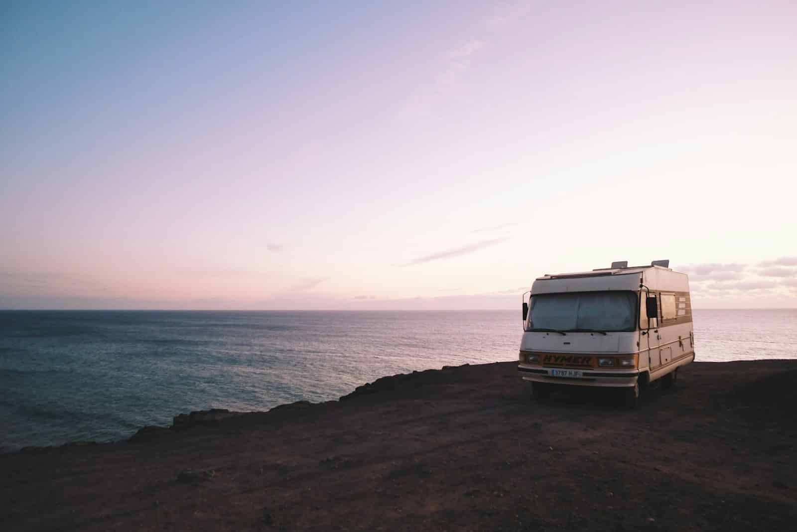 RV parked beside the edge of an island during sunset