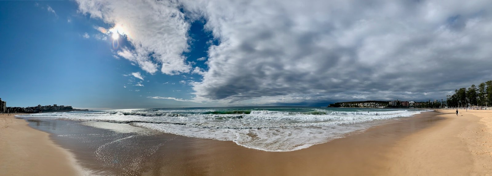 Ocean waves crashing on shore under a blue and white cloudy sky