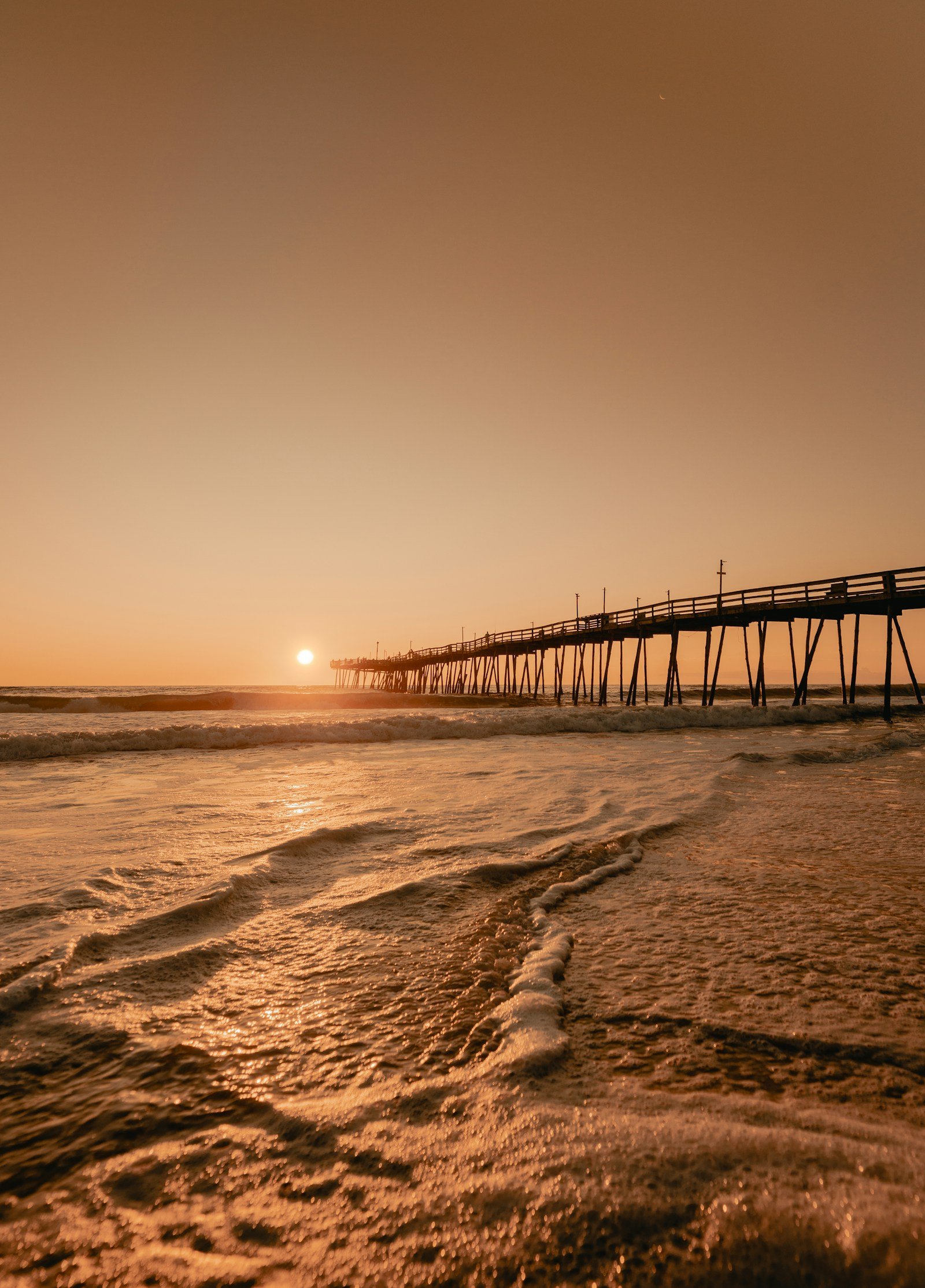 Wooden sound-side dock extending into calm water at sunset, Outer Banks