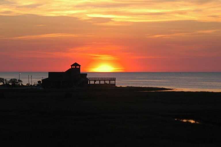 Sun setting over the ocean with a beach house in the foreground, Outer Banks