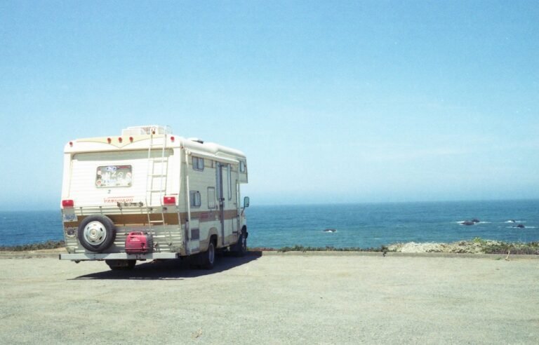 Camper van parked on a sandy beach during daytime