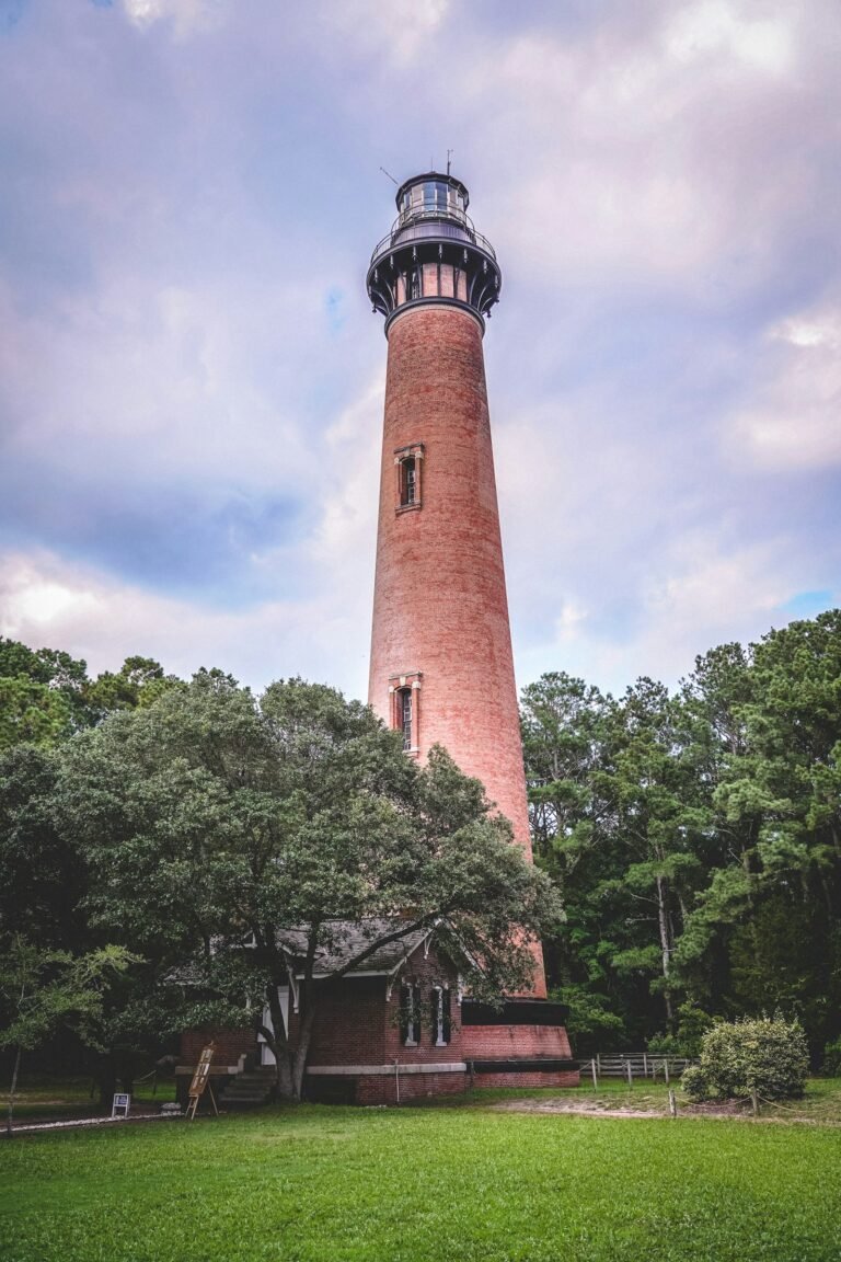 Currituck Beach Lighthouse red brick tower rising above green trees, Corolla NC
