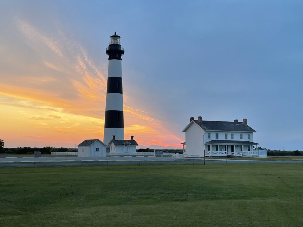 Warm sunrise light on the Bodie Island Lighthouse and the keepers' quarters beside it.