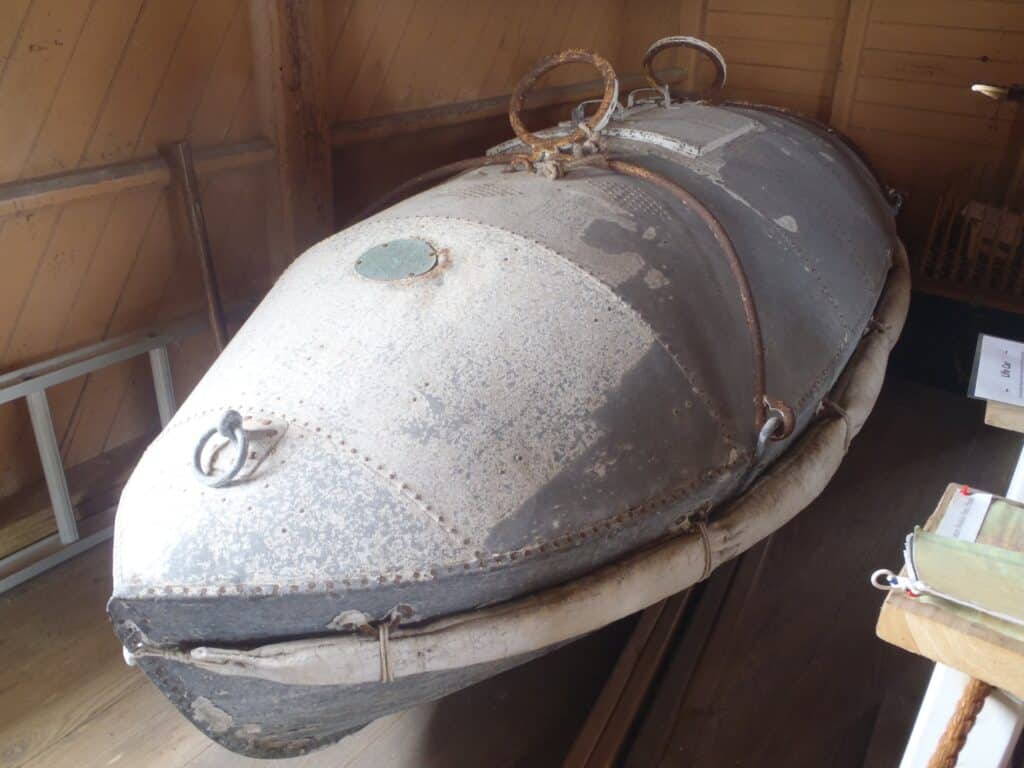 A riveted metal life car, an enclosed rescue capsule once hauled by line between wreck and shore.