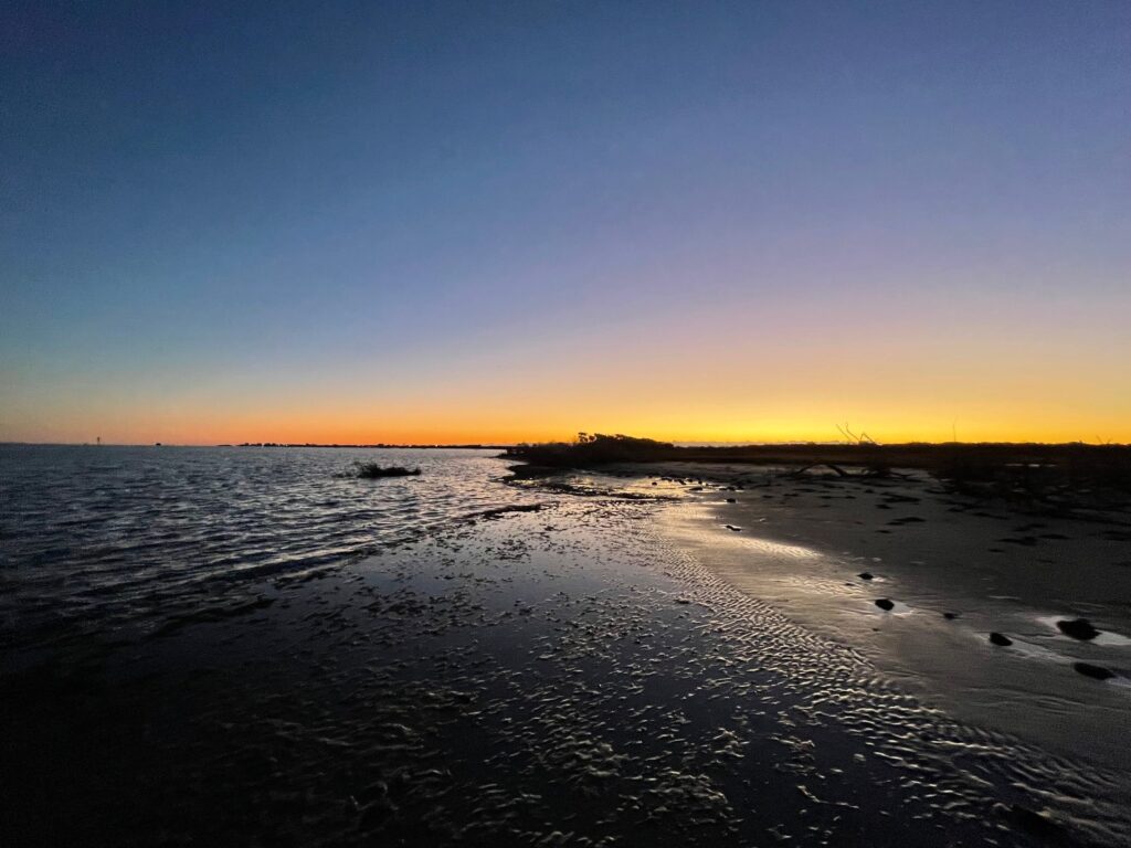 Low sun and still water along a sound shoreline at first light.