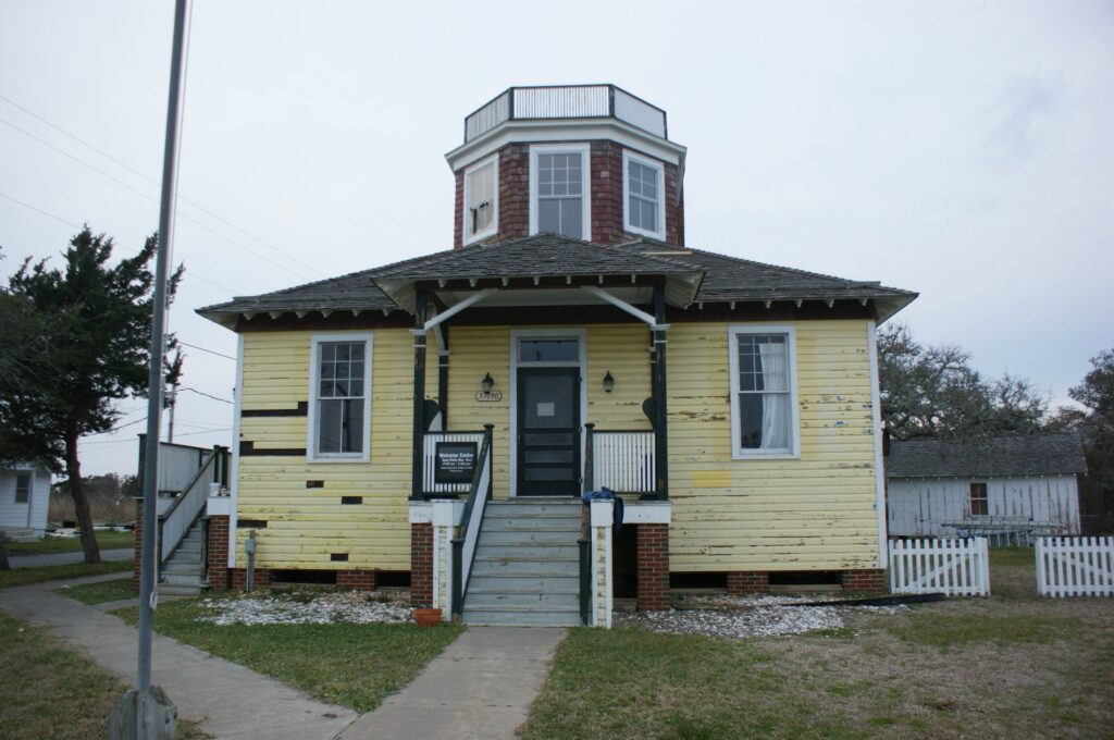 The restored yellow clapboard Hatteras Weather Bureau Station building with its covered porch.