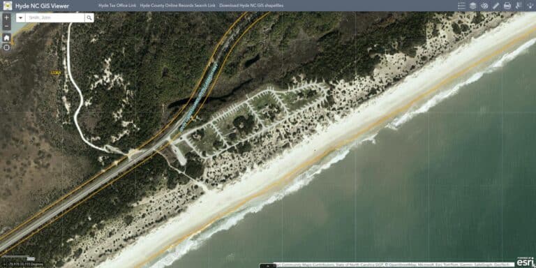 Aerial view of Ocracoke Campground on Ocracoke Island, showing campsite loops between NC Highway 12 and the Atlantic Ocean beach and dunes