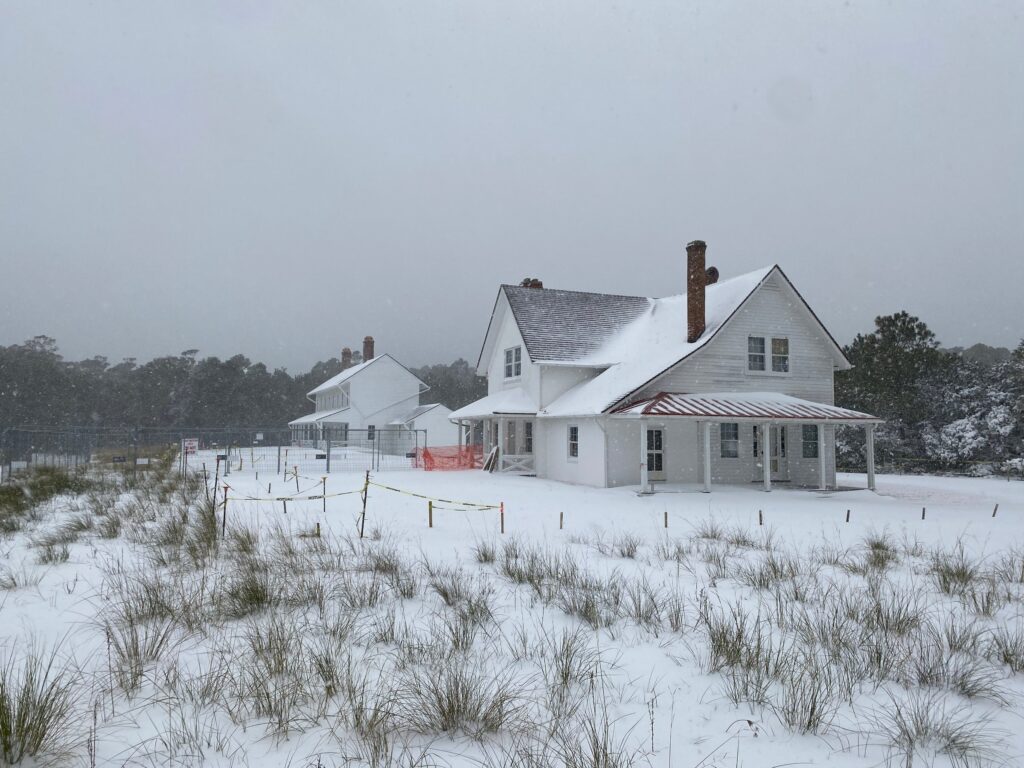 The Cape Hatteras Principal Keeper's Quarters and Double Keepers' Quarters under a light covering of snow.